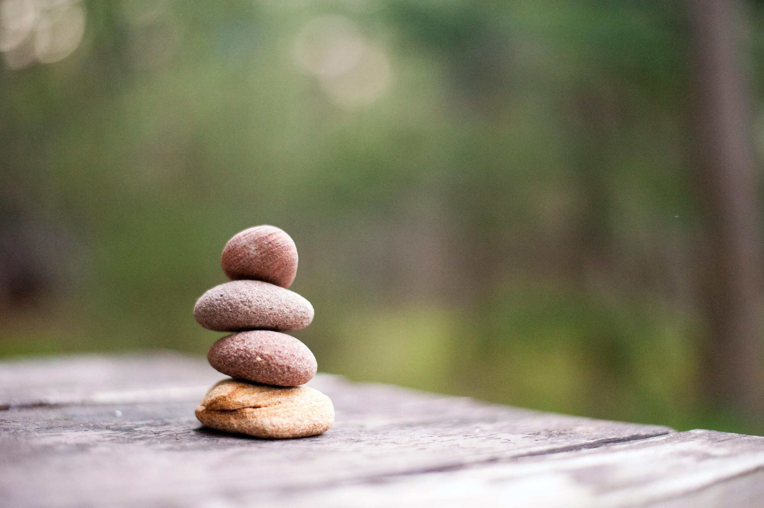 Stacked stones symbolizing balance and alignment on a wooden surface with blurred nature background.